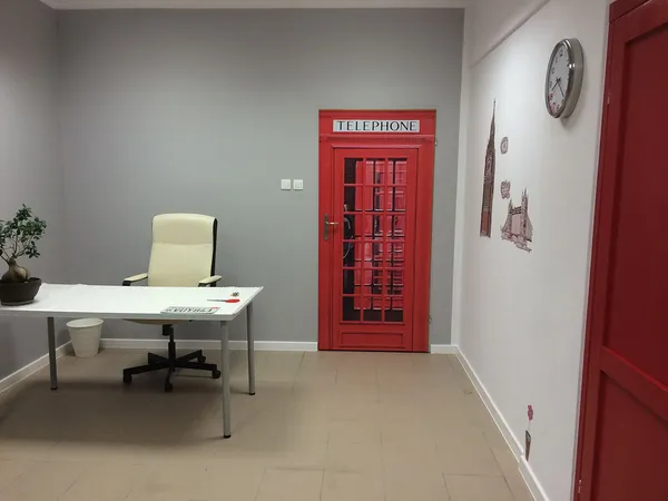 Sala z biurkiem, fotelem i dekoracją czerwonej brytyjskiej budki telefonicznej na ścianie